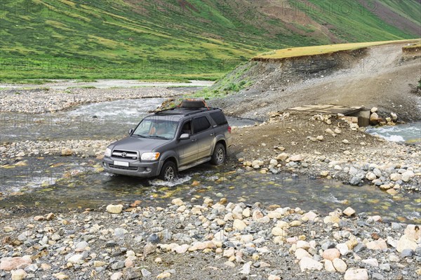 Off-road vehicle crossing a mountain river at Tosor Pass