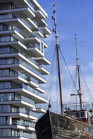 Old fishing boat and new flat under construction for the Oosteroever real estate project in the port of Ostend on the Belgian North Sea coast