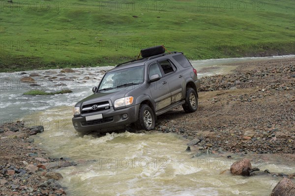 Off-road vehicle crossing a mountain river at Tosor Pass