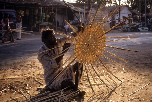 Basket maker weaving bamboo strips baskets