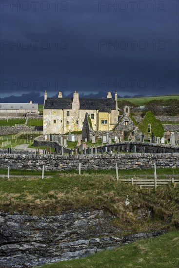 Black storm clouds rolling in over ruined church and the Balnakeil House