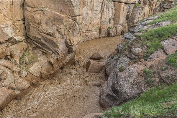 Muddy mountain river flowing through a narrow gorge