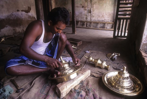 Artisan working on brass lamp
