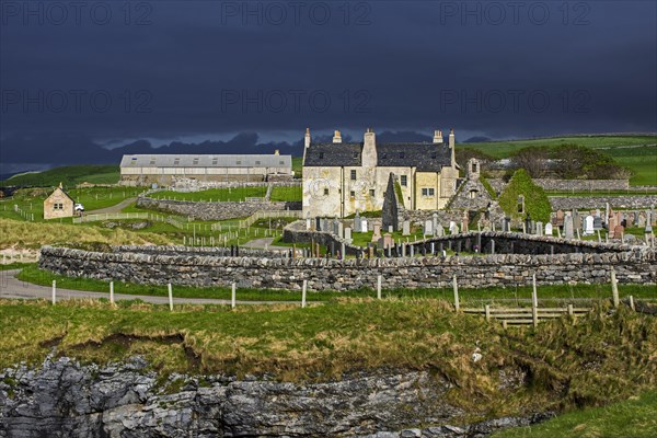 Black storm clouds rolling in over ruined church and the Balnakeil House