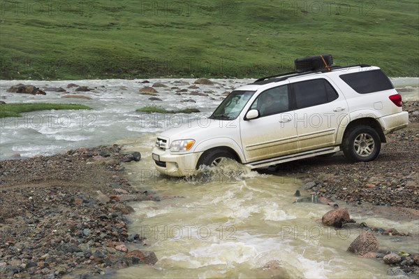 Off-road vehicle crossing a mountain river at Tosor Pass