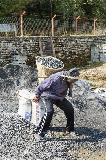 Nepalese man carrying stones for construction on his back