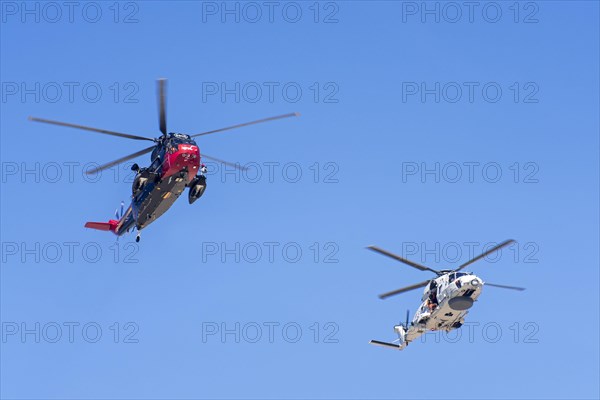 Westland Sea King MK48 SAR and NH90-NFH Caiman NATO frigate helicopter of the Belgian Navy in flight during a coastal search and rescue mission