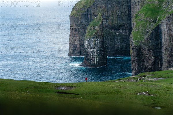 A person standing in the distance in front of Asmundarstakkur cliff