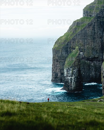 A person standing in the distance in front of Asmundarstakkur cliff