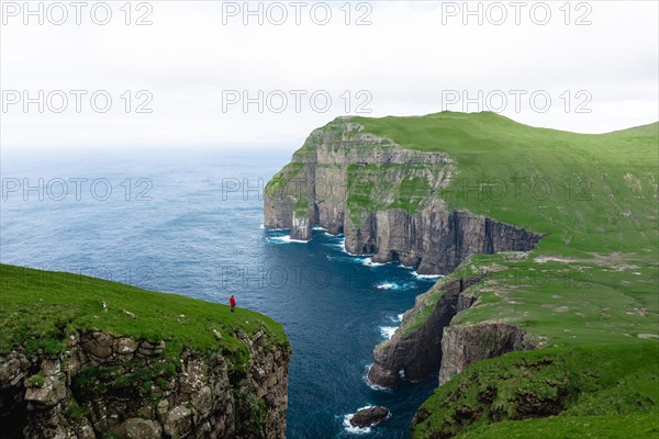 A person standing in the distance in front of Asmundarstakkur cliff