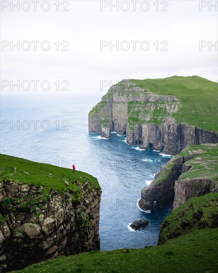 A person standing in the distance in front of Asmundarstakkur cliff