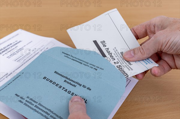 Man puts his folded ballot paper into the ballot paper envelope for the election of members of the German Bundestag on 26.09.2021