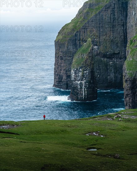 A person standing in the distance in front of Asmundarstakkur cliff