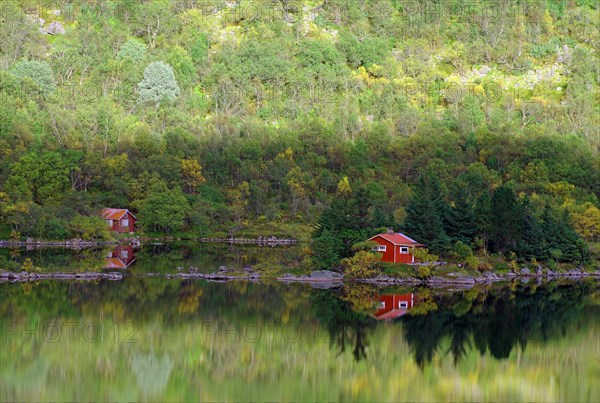 Red wooden houses reflected in a calm lake