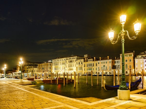Boat mooring in front of historic house facade on the Grand Canal at night