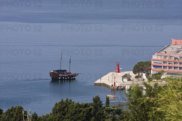 Antique sailing boat in front of a hotel complex in Lucija