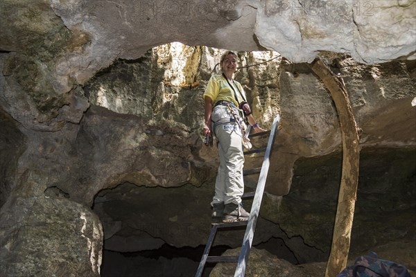 Woman climbing ladder in karst rock