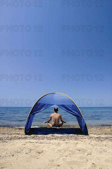 A man meditating on sand