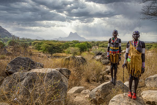 Traditional dressed young girls from the Laarim tribe standing on a rock