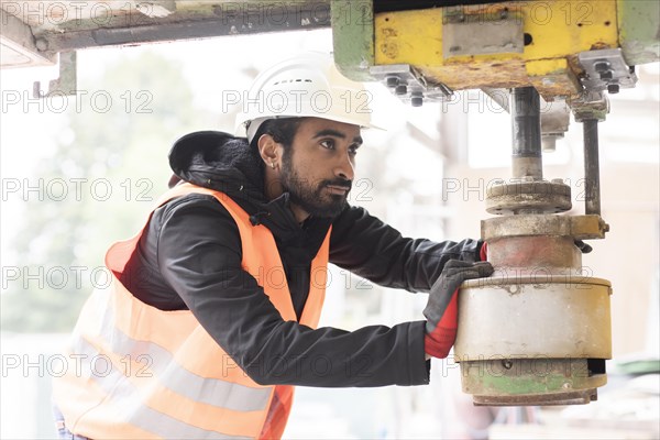 Technician with beard and helmet works in a workshop