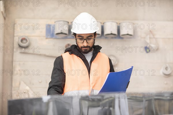 Technician with beard and helmet works in a workshop