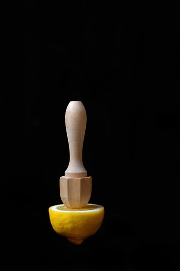 Lemon and lemon squeezer against a black background