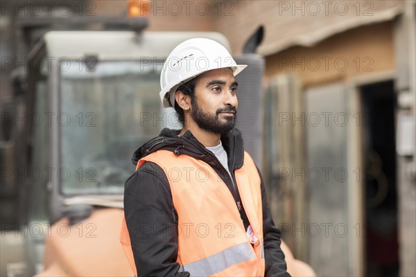 Technician with beard and helmet works in a workshop