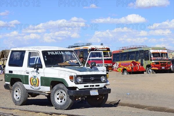 Policeman with police car in front of waiting public buses