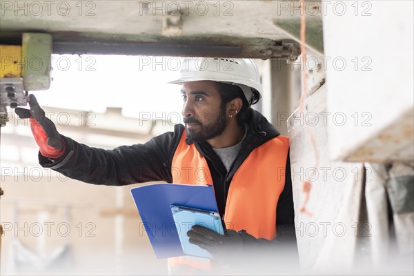 Technician with beard and helmet works in a workshop