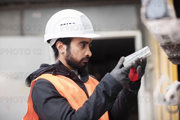 Technician with beard and helmet works in a workshop