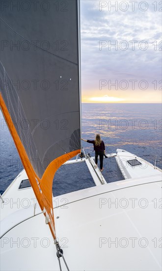 Young woman standing leaning against foresail