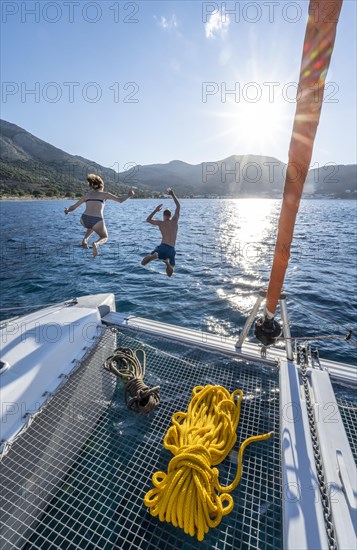 Young woman and young man jumping into the water