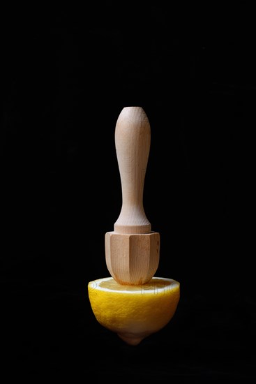 Lemon and lemon squeezer against a black background