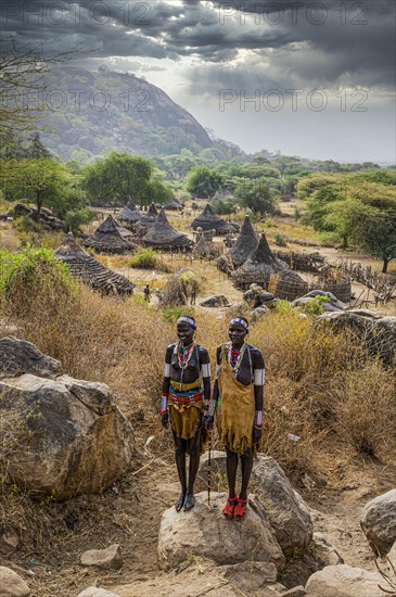 Traditional dressed young girls from the Laarim tribe standing on a rock