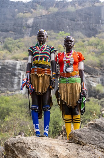 Traditional dressed young girls from the Laarim tribe standing on a rock