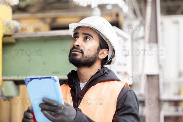 Technician with beard and helmet works in a workshop