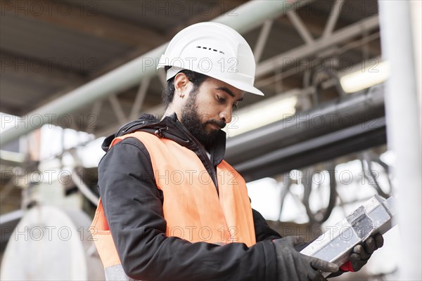 Technician with beard and helmet works in a workshop