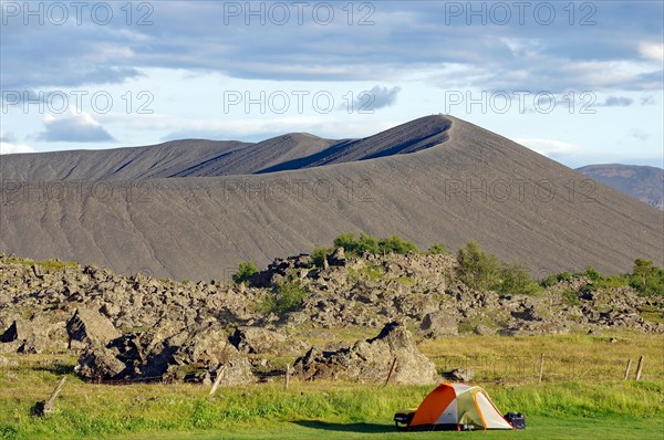 Tent in front of volcanic cone and lava