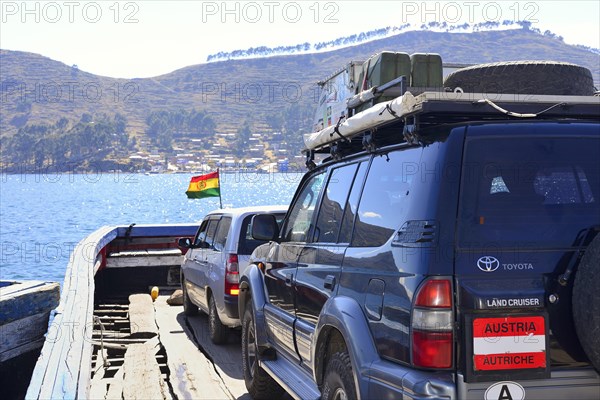 Austrian off-road vehicle on a simple ferry boat across the Strait of Tiquina