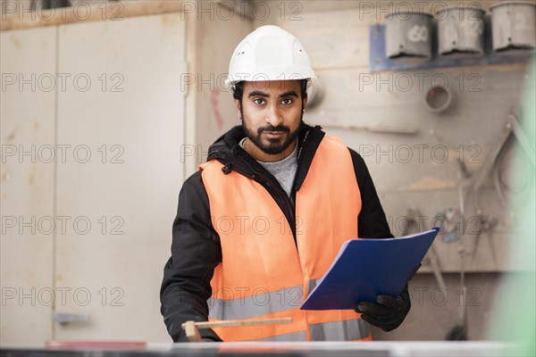 Technician with beard and helmet works in a workshop