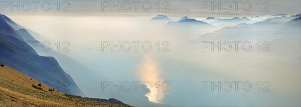 Lake Garda in the morning mist with Lake Garda mountains and Bergamo Alps