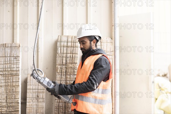 Technician with beard and helmet works in a workshop
