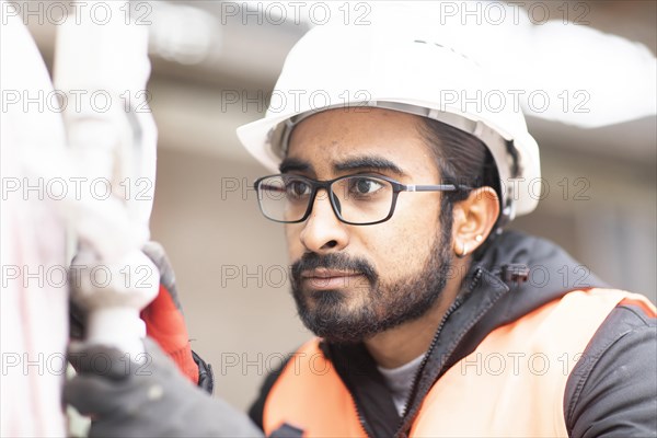 Technician with beard and helmet works in a workshop