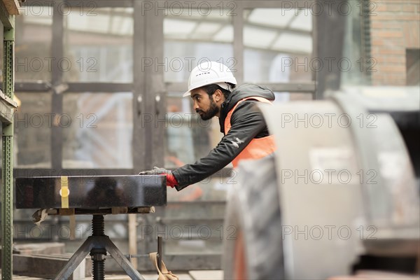 Technician with beard and helmet works in a workshop