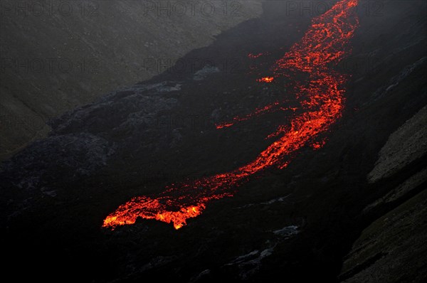 Glowing lava flows down mountainside