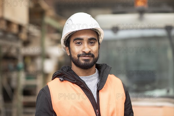 Technician with beard and helmet works in a workshop