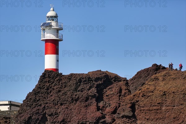 Red and white lighthouse on rocky coast