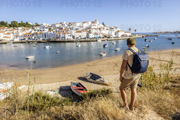 Cityscape of Ferragudo with a tourist admiring this town in the foreground