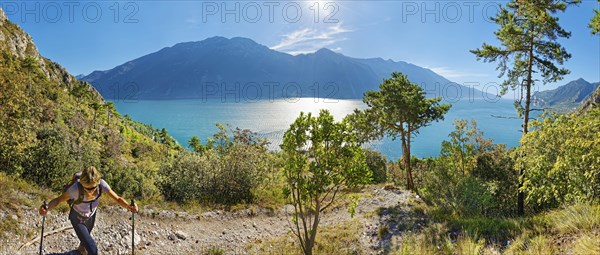 Hiker on the western shore of Lake Garda with the mountain range Monte Baldo
