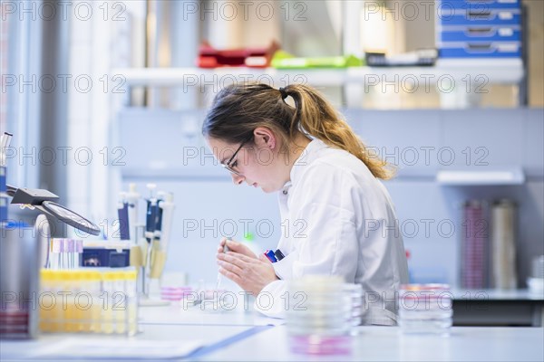 Lab technician with sample in petri dish working in a lab with lab equipment